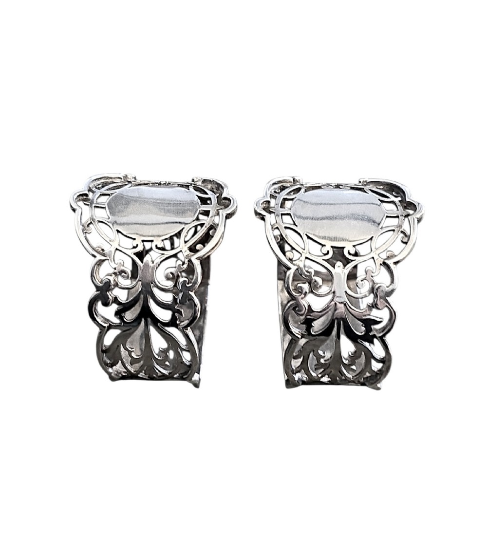 A pair of Edwardian pierced sterling silver napkin rings with unengraved cartouches presented in a dark velvet-lined fitted box. View III