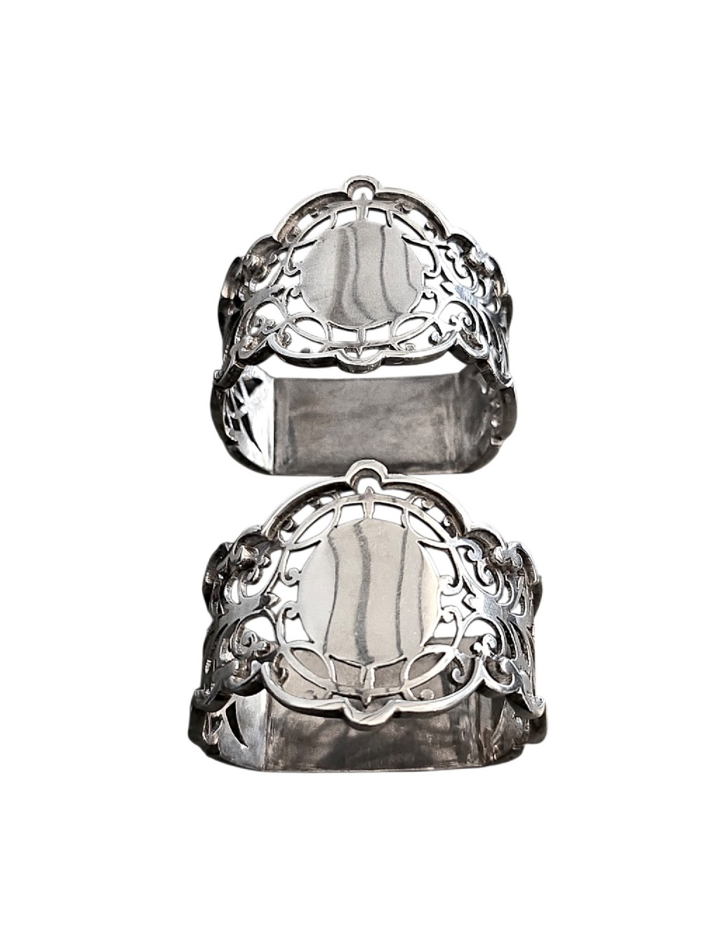 A pair of Edwardian pierced sterling silver napkin rings with unengraved cartouches presented in a dark velvet-lined fitted box. View V