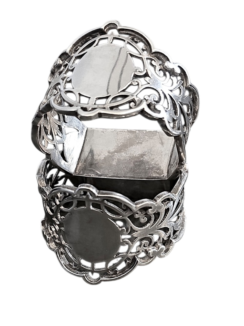 A pair of Edwardian pierced sterling silver napkin rings with unengraved cartouches presented in a dark velvet-lined fitted box. View VI