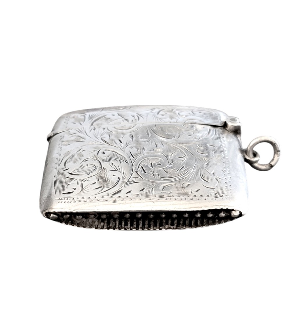A small rectangular sterling silver vesta case with hand-engraved scrollwork, a central vacant shield cartouche, and a side suspension ring. View V
