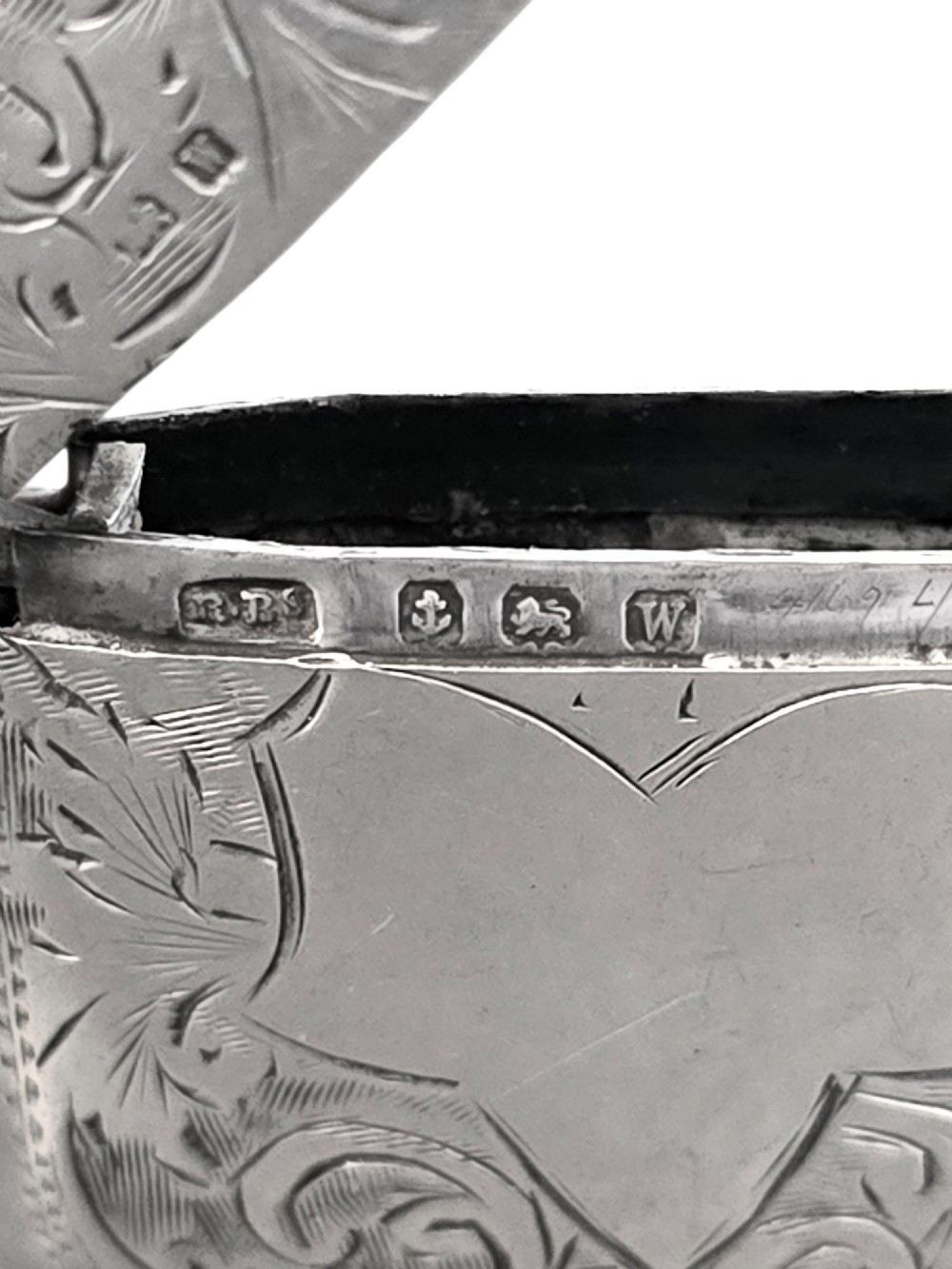 A small rectangular sterling silver vesta case with hand-engraved scrollwork, a central vacant shield cartouche, and a side suspension ring. View VI