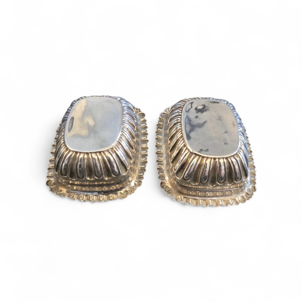 A pair of Edwardian sterling silver rectangular open salt cellars featuring fluted sides, gadrooned rims, and gilded interiors. View III