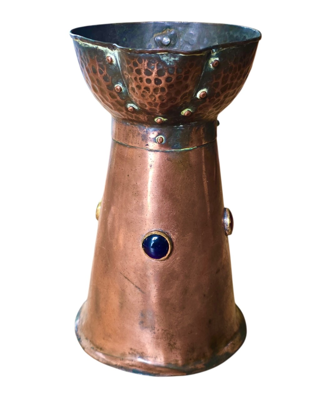 An antique Arts and Crafts copper jug featuring a planished finish, riveted collar, brass handle, and inset coloured cabochons. View IV