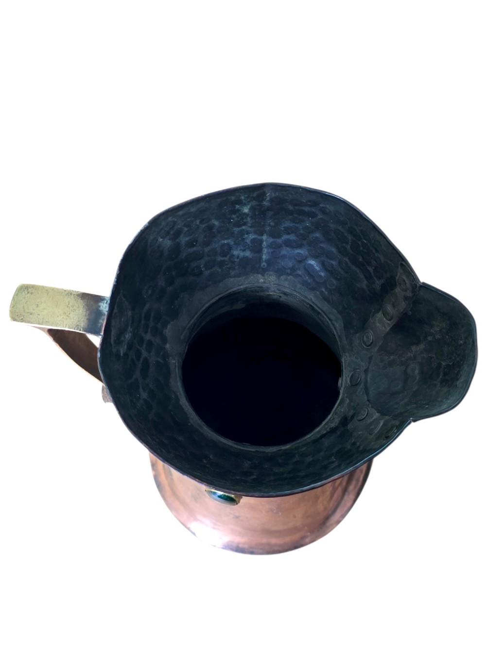An antique Arts and Crafts copper jug featuring a planished finish, riveted collar, brass handle, and inset coloured cabochons. View VI