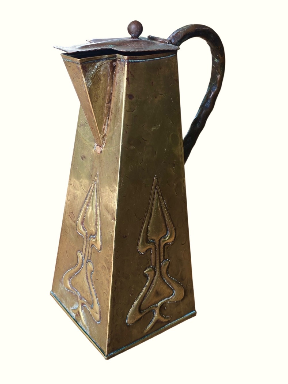 A tapered square brass water jug with a fitted metal lid, curved handle, and embossed stylised Art Nouveau motifs on the sides.
