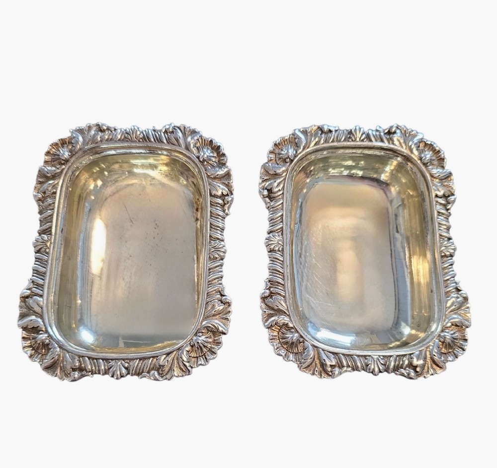A pair of Regency sterling silver rectangular table salts featuring gadrooned rims and gilded interiors on shaped pedestal bases. View III