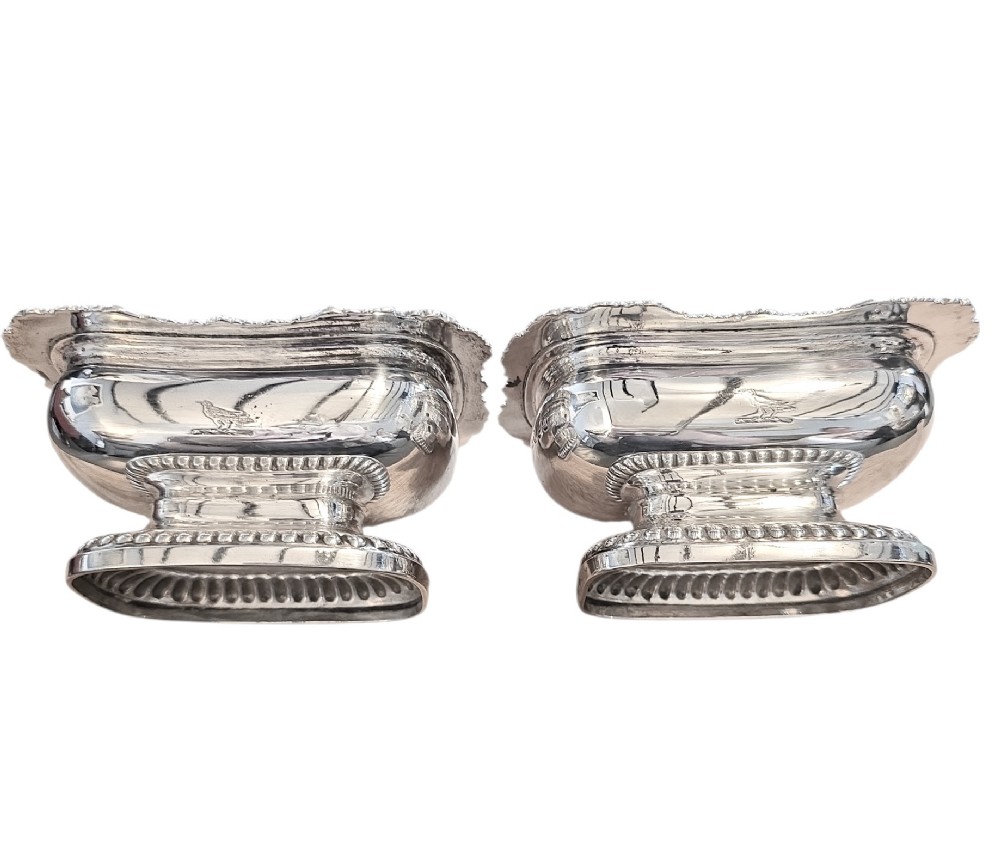 A pair of Regency sterling silver rectangular table salts featuring gadrooned rims and gilded interiors on shaped pedestal bases. View IV
