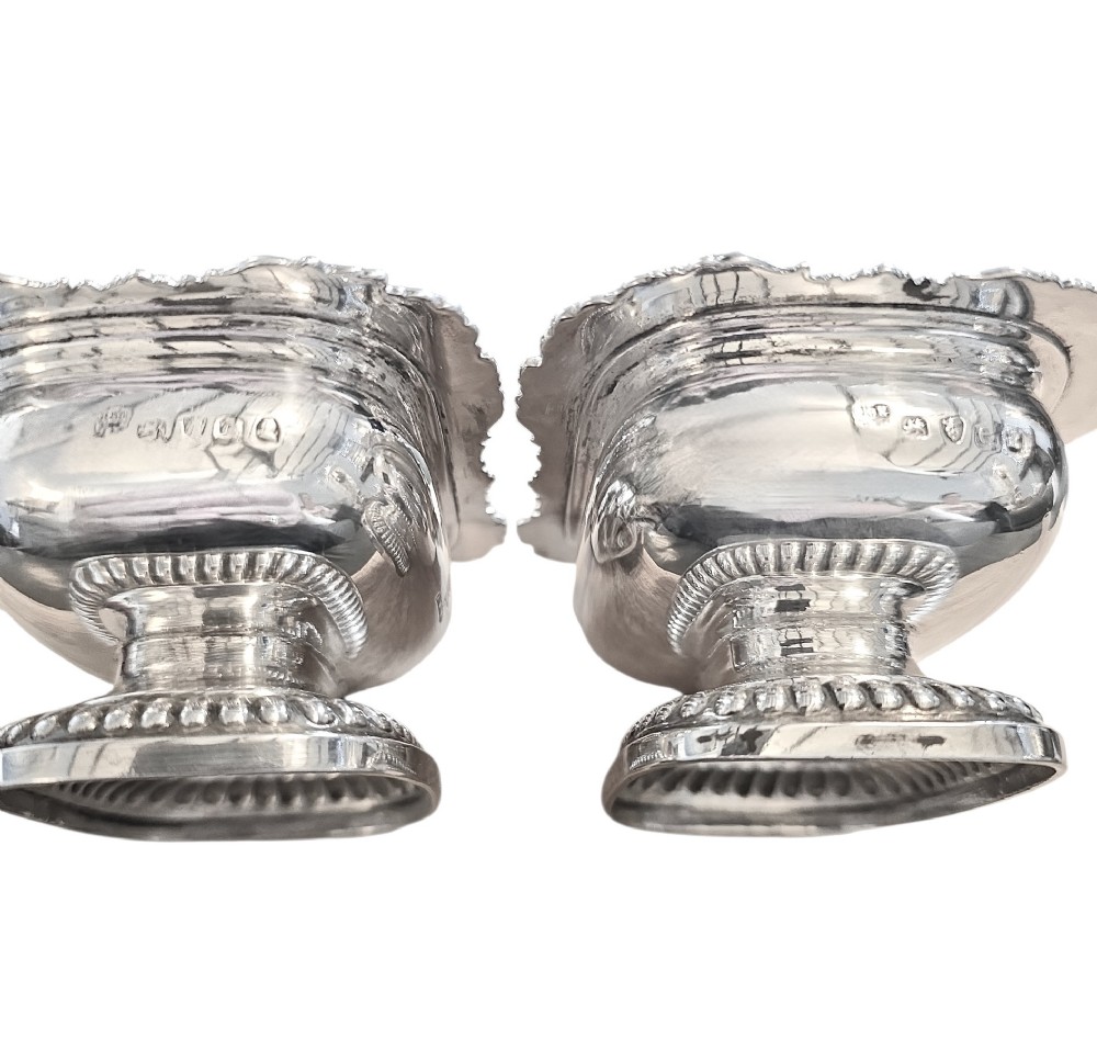 A pair of Regency sterling silver rectangular table salts featuring gadrooned rims and gilded interiors on shaped pedestal bases. View V