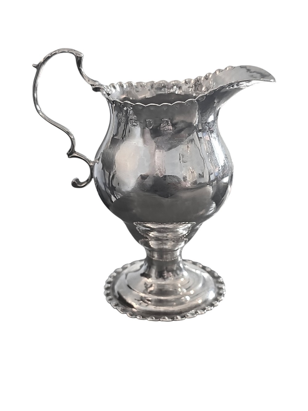A George III sterling silver cream jug featuring a baluster shape, scalloped rim, double-scroll handle, and pedestal base. View II