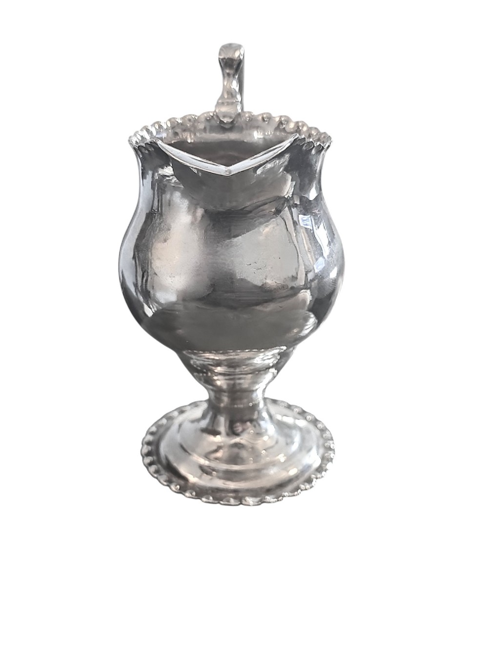 A George III sterling silver cream jug featuring a baluster shape, scalloped rim, double-scroll handle, and pedestal base. View III