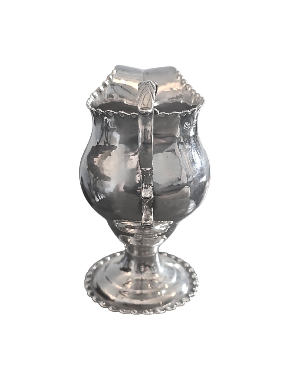 A George III sterling silver cream jug featuring a baluster shape, scalloped rim, double-scroll handle, and pedestal base. View V