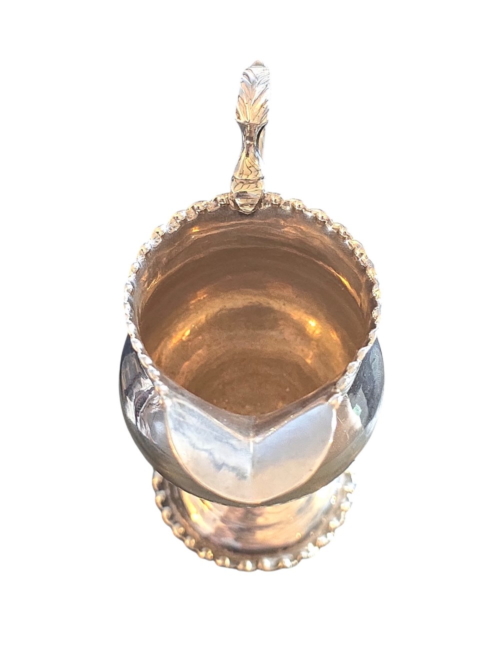 A George III sterling silver cream jug featuring a baluster shape, scalloped rim, double-scroll handle, and pedestal base. View VII
