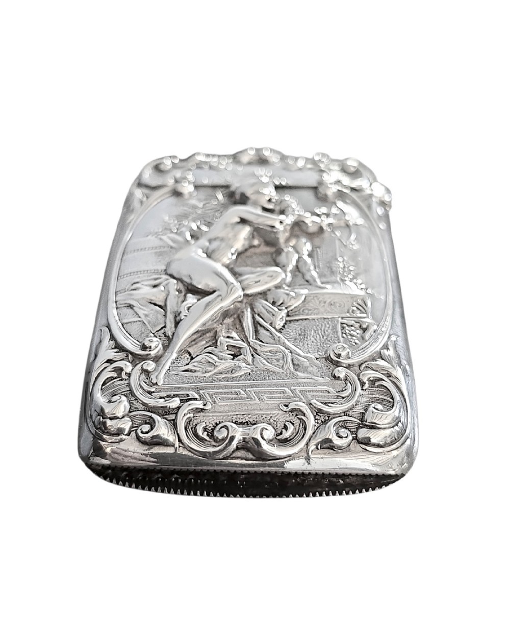 An Edwardian sterling silver vesta case featuring embossed relief detailing of Cupid and Psyche framed by scrollwork borders. View IV
