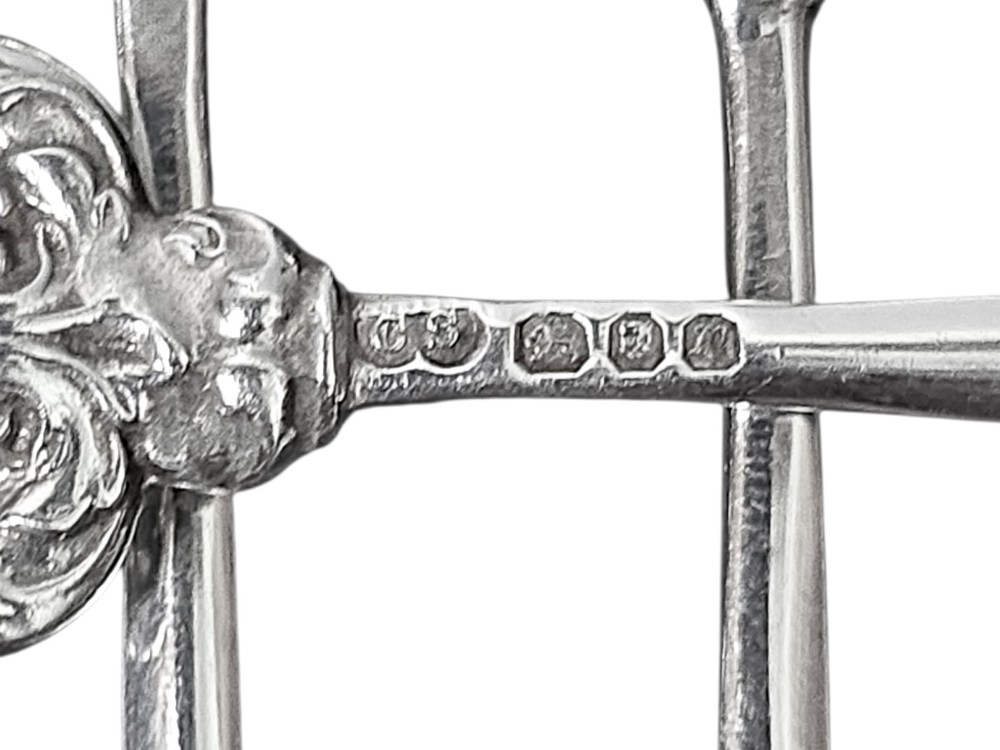 A set of eight sterling silver hors doeuvre skewers arranged in a fan shape, featuring ornate openwork scrollwork handles and tapered pins. View III