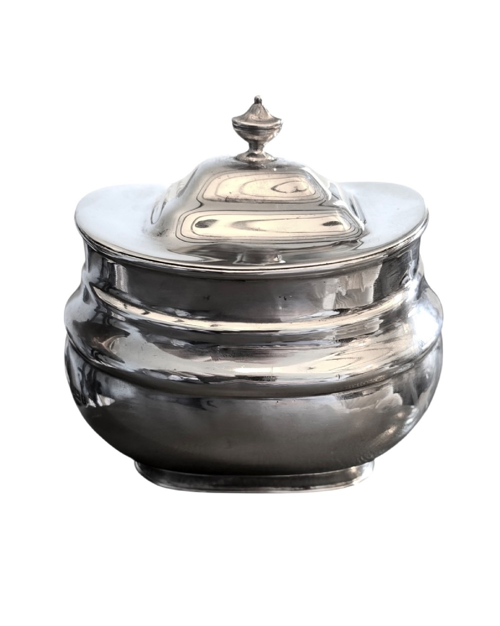 An Edwardian sterling silver tea caddy featuring a bulbous body, stepped lid, and urn-shaped finial.