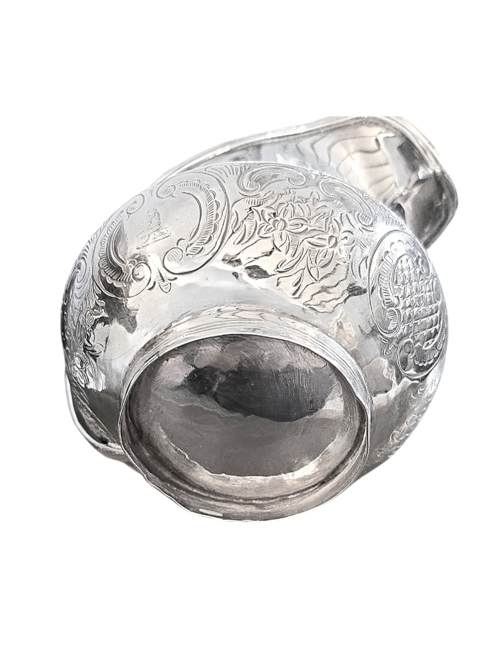 A George III sterling silver cream jug with chased scroll decoration, an angular high loop handle, and a circular foot. View V