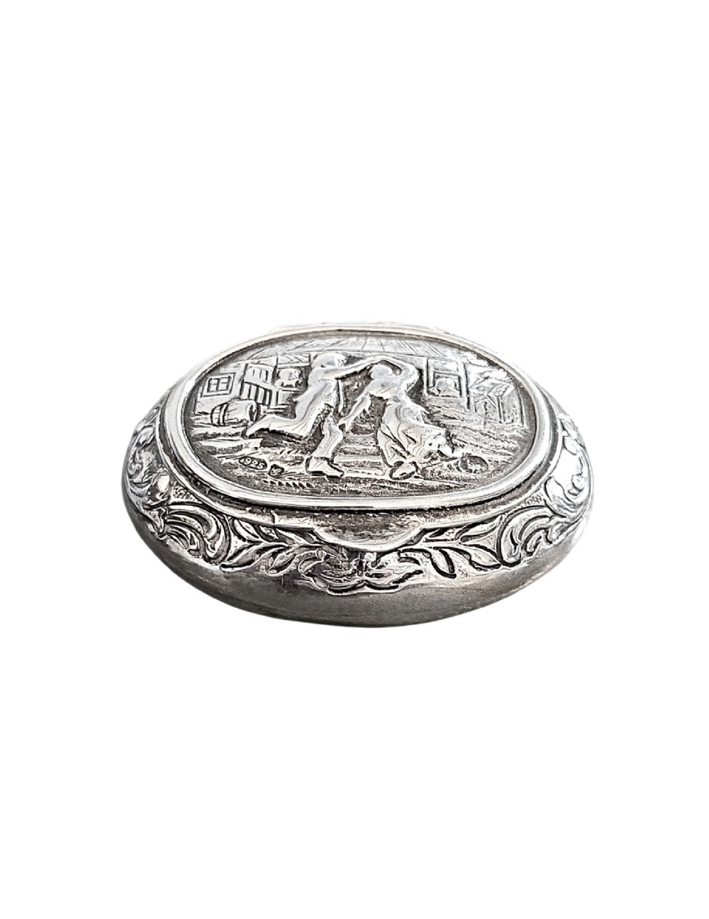 An oval antique sterling silver snuff box featuring an embossed central scene of dancing figures, framed by scrollwork borders. View II