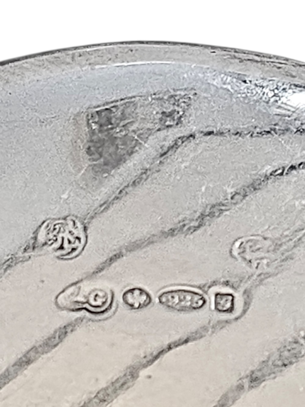 An oval antique sterling silver snuff box featuring an embossed central scene of dancing figures, framed by scrollwork borders. View V