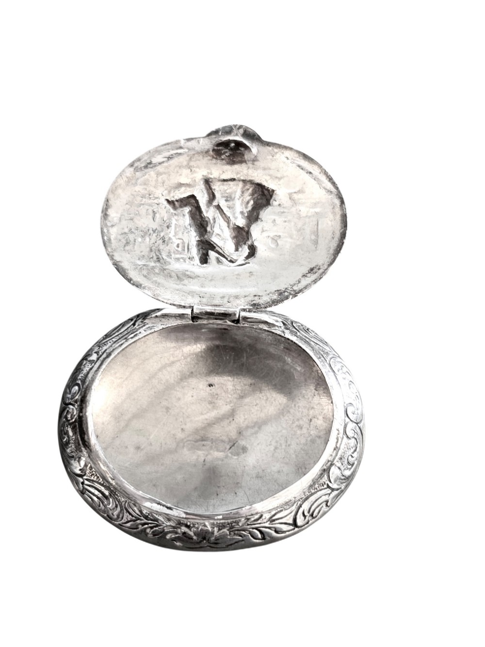 An oval antique sterling silver snuff box featuring an embossed central scene of dancing figures, framed by scrollwork borders. View VI