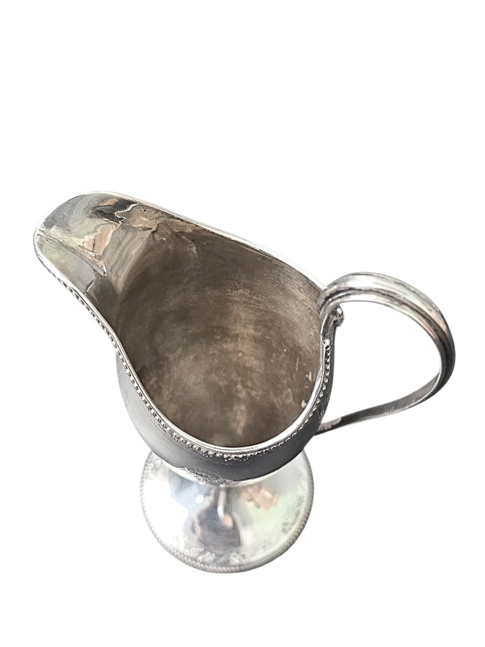 A George III sterling silver helmet-shaped cream jug with bright-cut floral engraving, a beaded rim, a high loop handle, and a circular pedestal foot. View VI