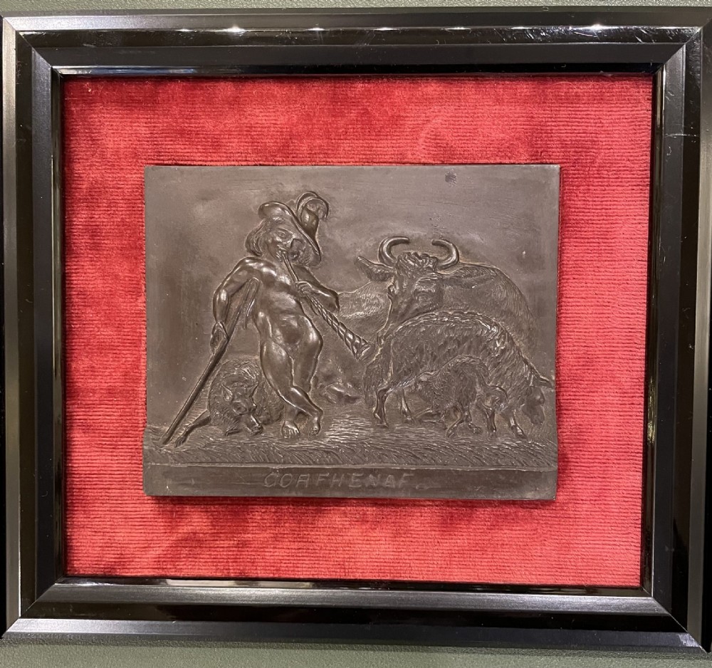 A set of framed hand-carved dark Welsh slate relief plaques mounted against red fabric backgrounds within black moulded frames. View IV