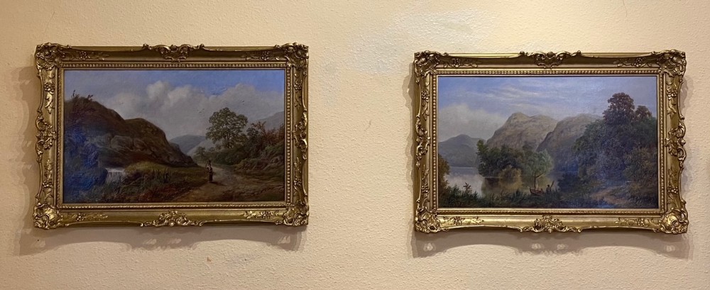 A pair of late Victorian oil landscape paintings depicting natural scenes of rivers and mountains, housed in matching ornate gold gilt frames.