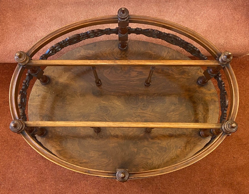 An oval Victorian walnut music canterbury featuring three upper compartments, turned finials, pierced fretwork, a single lower drawer, turned legs, and brass castors. View XI