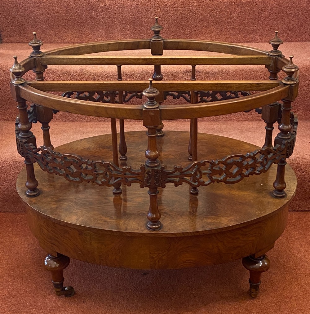 An oval Victorian walnut music canterbury featuring three upper compartments, turned finials, pierced fretwork, a single lower drawer, turned legs, and brass castors. View XIII