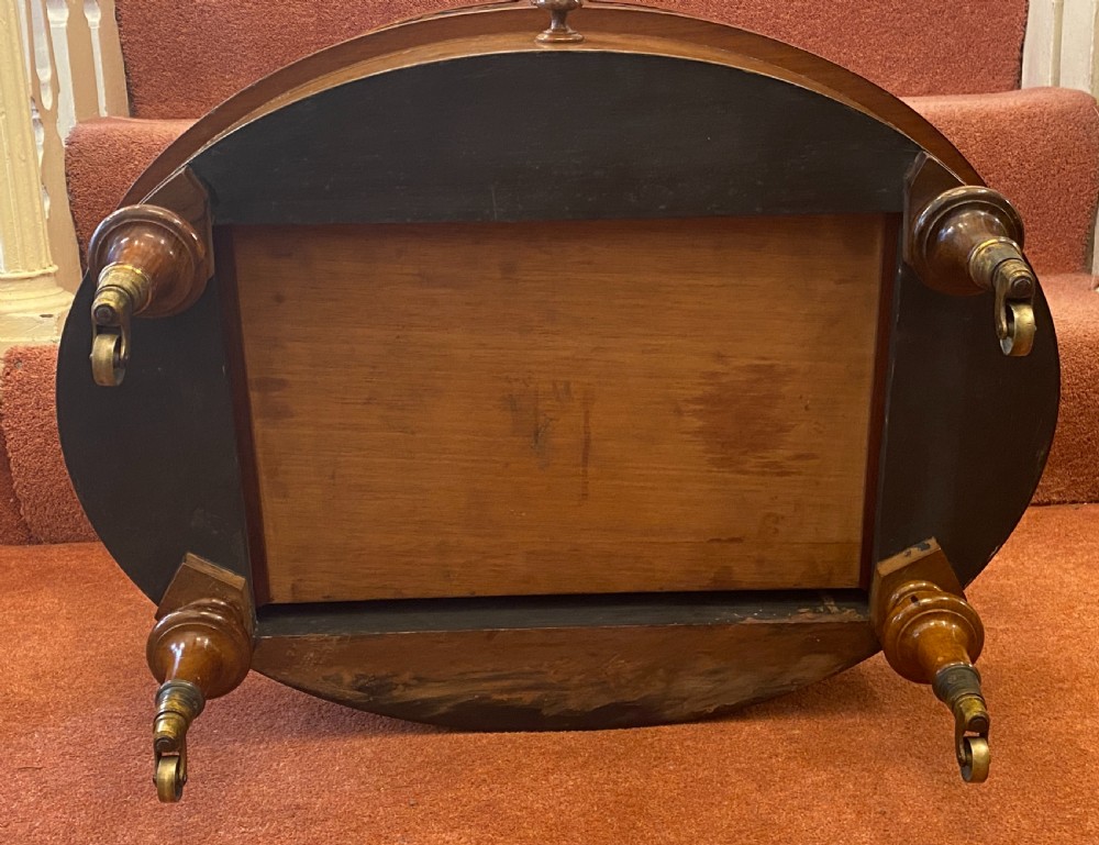 An oval Victorian walnut music canterbury featuring three upper compartments, turned finials, pierced fretwork, a single lower drawer, turned legs, and brass castors. View XV