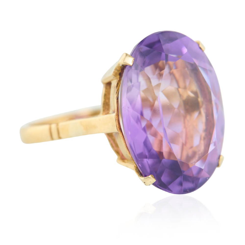 A 9ct yellow gold ring featuring a large oval faceted purple amethyst stone in a multi-claw basket setting.