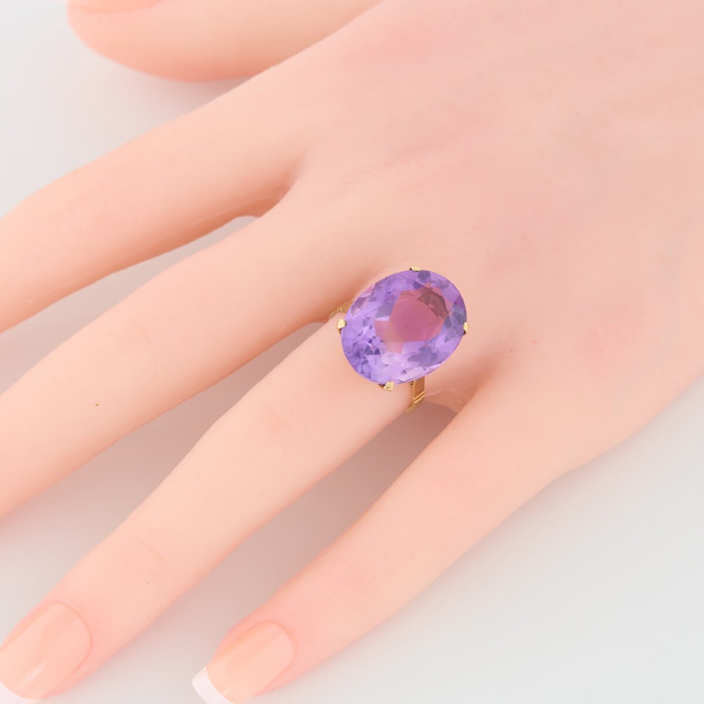 A 9ct yellow gold ring featuring a large oval faceted purple amethyst stone in a multi-claw basket setting. View II