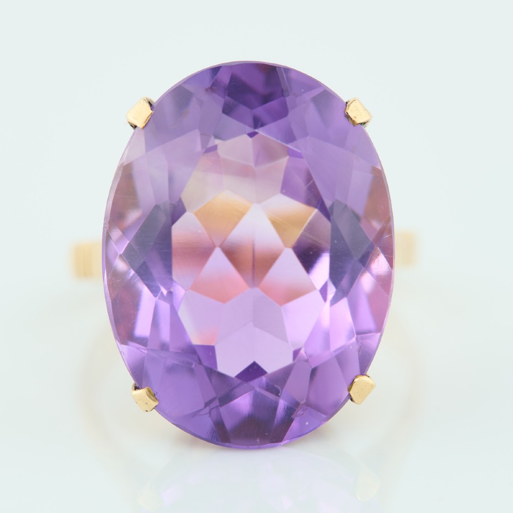 A 9ct yellow gold ring featuring a large oval faceted purple amethyst stone in a multi-claw basket setting. View III