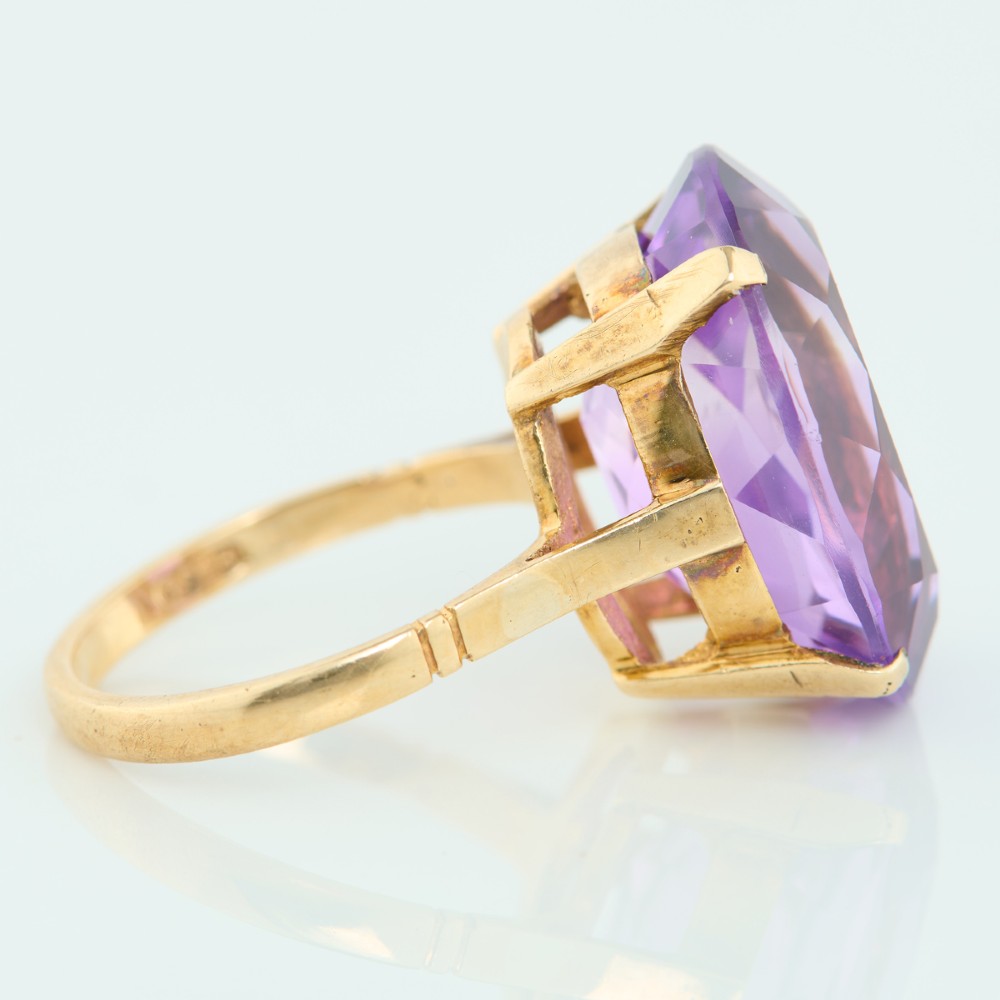 A 9ct yellow gold ring featuring a large oval faceted purple amethyst stone in a multi-claw basket setting. View IV