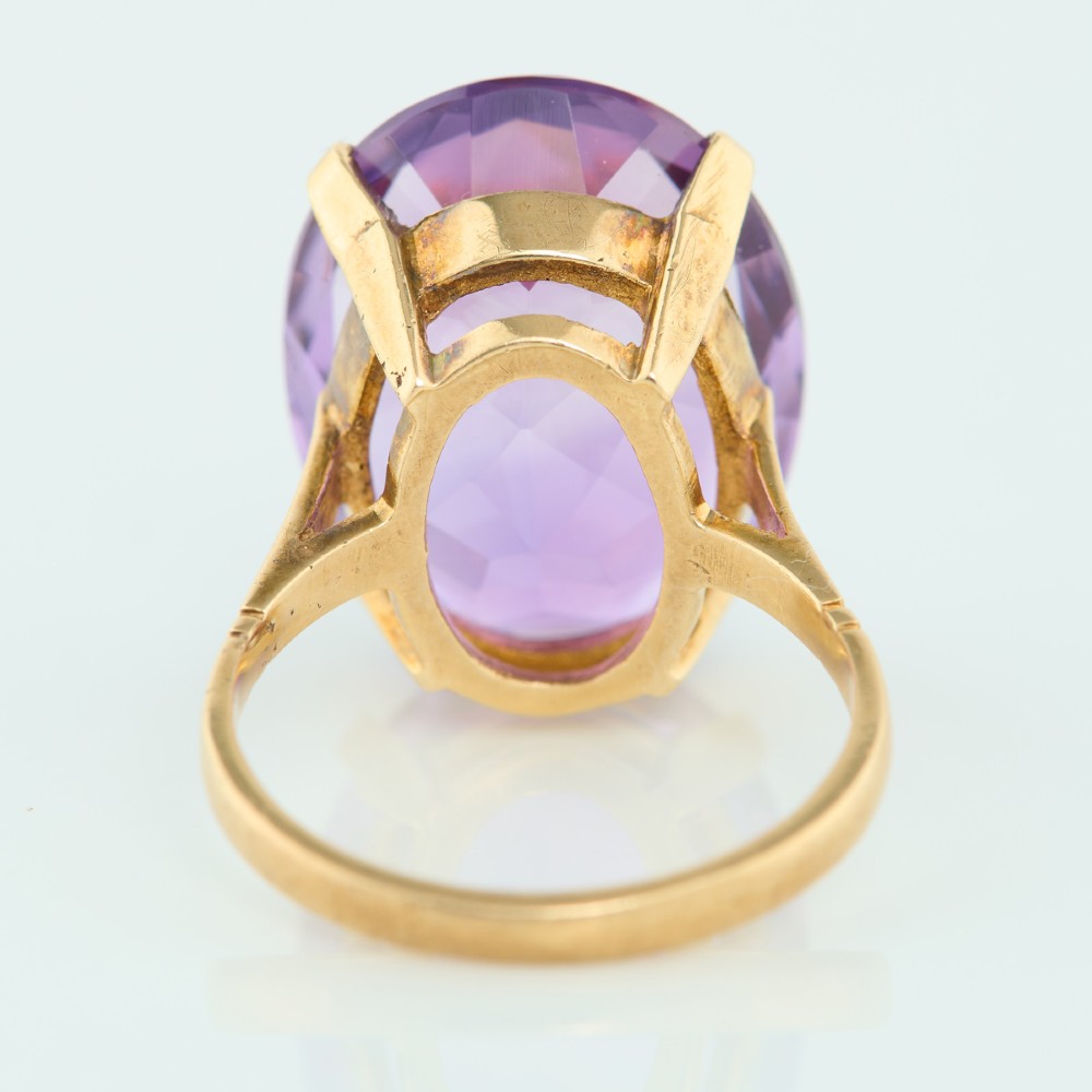 A 9ct yellow gold ring featuring a large oval faceted purple amethyst stone in a multi-claw basket setting. View V