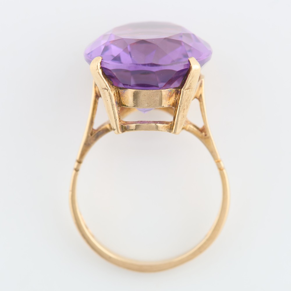 A 9ct yellow gold ring featuring a large oval faceted purple amethyst stone in a multi-claw basket setting. View VI