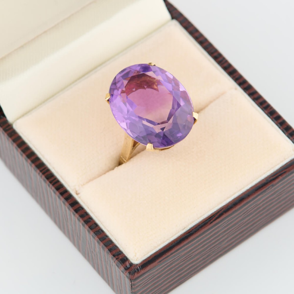 A 9ct yellow gold ring featuring a large oval faceted purple amethyst stone in a multi-claw basket setting. View VII