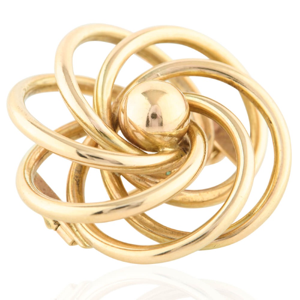 A 1950s 9ct yellow gold brooch featuring a central polished sphere surrounded by concentric swirling wire loops.
