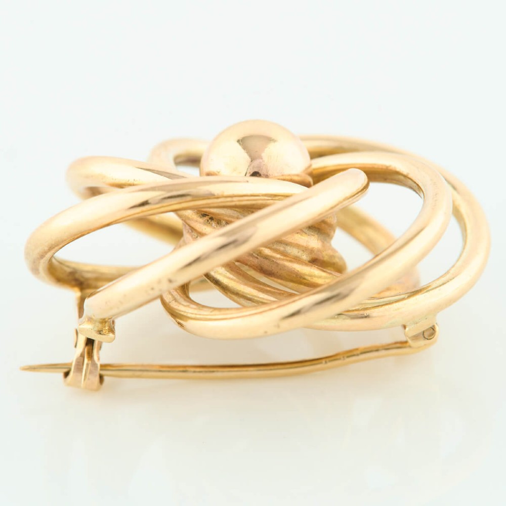 A 1950s 9ct yellow gold brooch featuring a central polished sphere surrounded by concentric swirling wire loops. View V