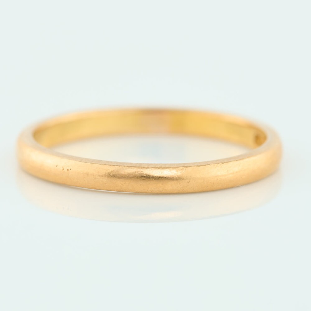 A plain 22ct yellow gold wedding band displaying a polished surface and classic rounded profile. View III