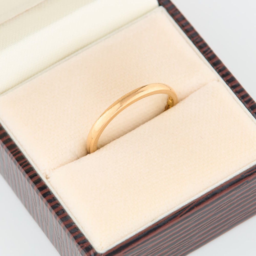 A plain 22ct yellow gold wedding band displaying a polished surface and classic rounded profile. View VI