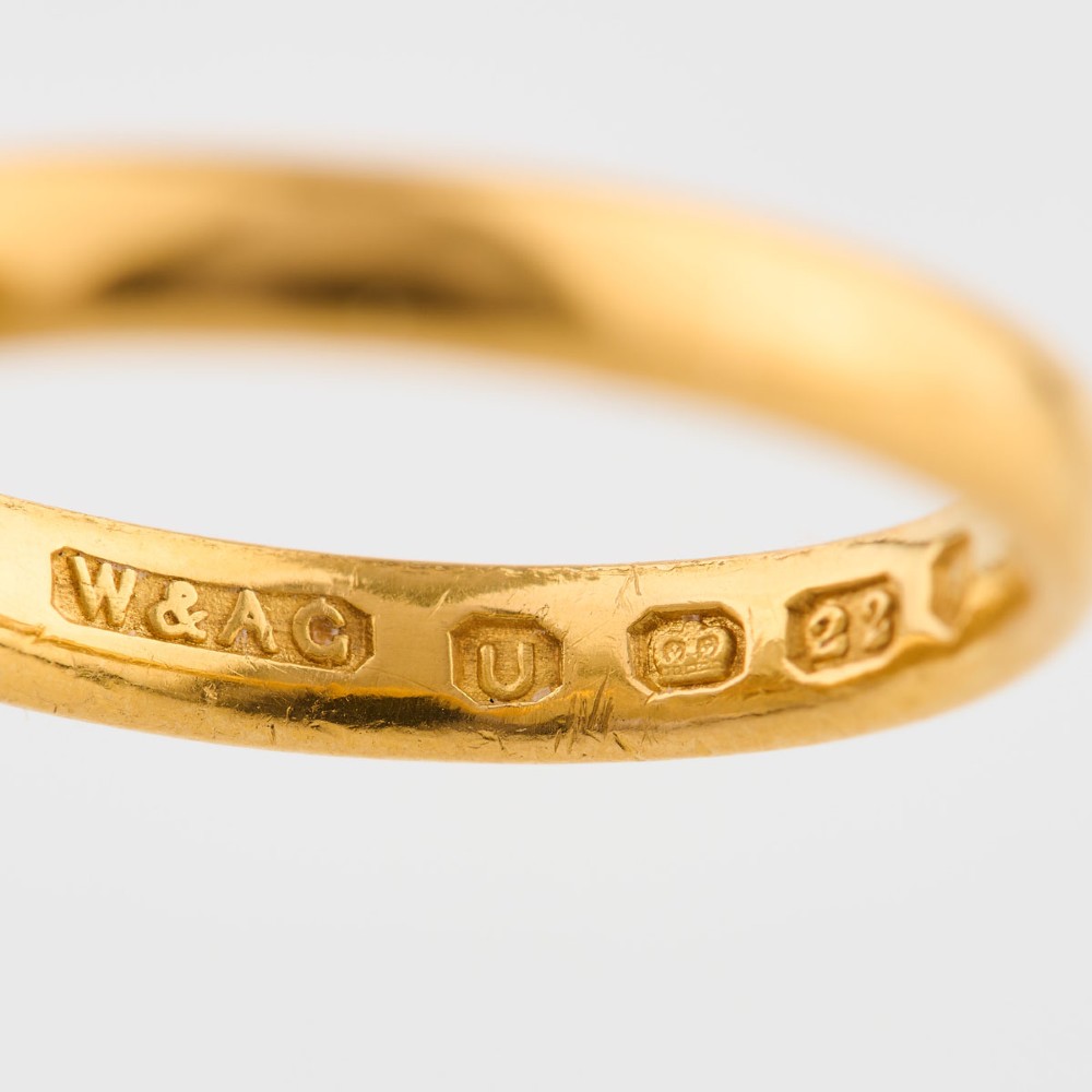 A plain 22ct yellow gold wedding band displaying interior hallmarks. View IV