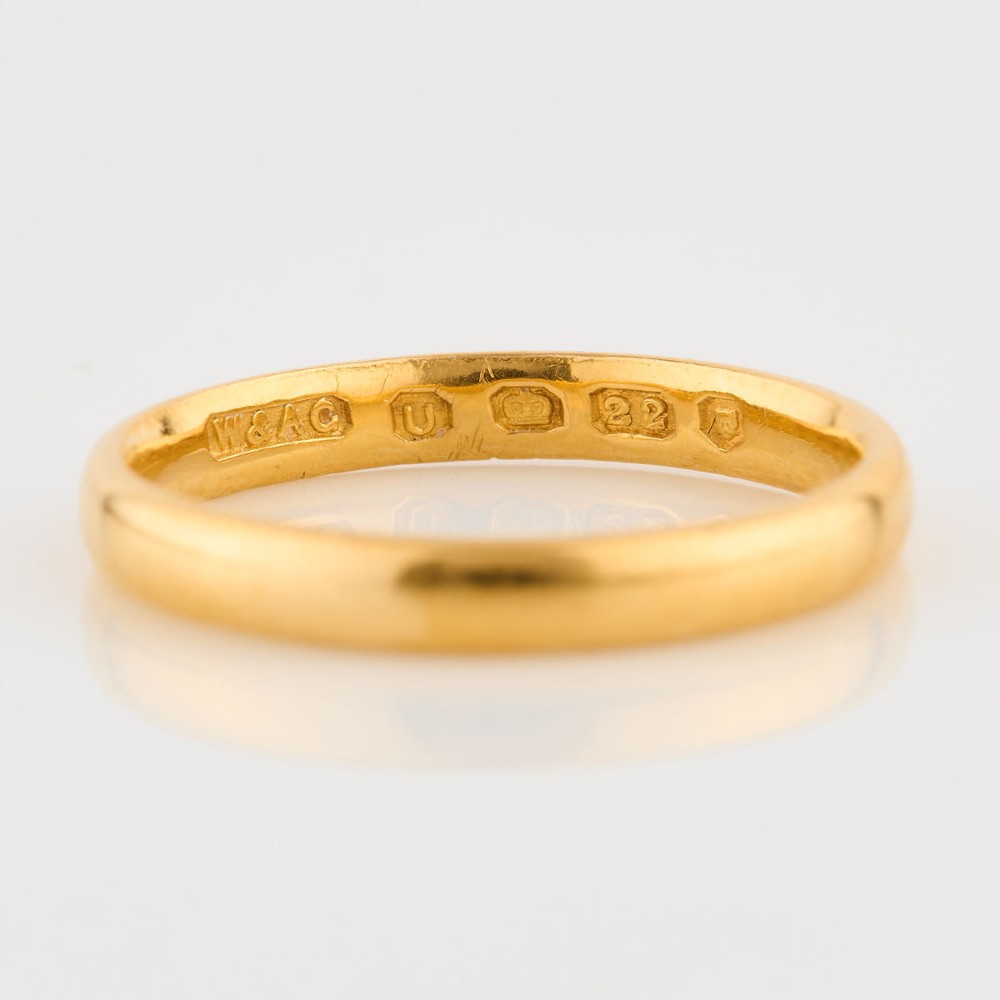 A plain 22ct yellow gold wedding band displaying interior hallmarks. View V