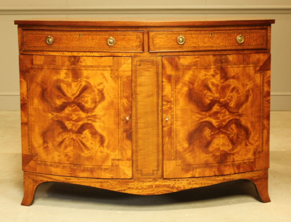 AN EDWARDIAN SATINWOOD BOW FRONTED TWO DOOR SIDEBOARD.