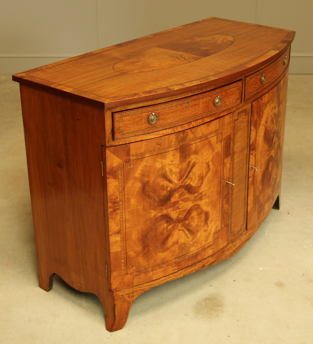 AN EDWARDIAN SATINWOOD BOW FRONTED TWO DOOR SIDEBOARD. View VII