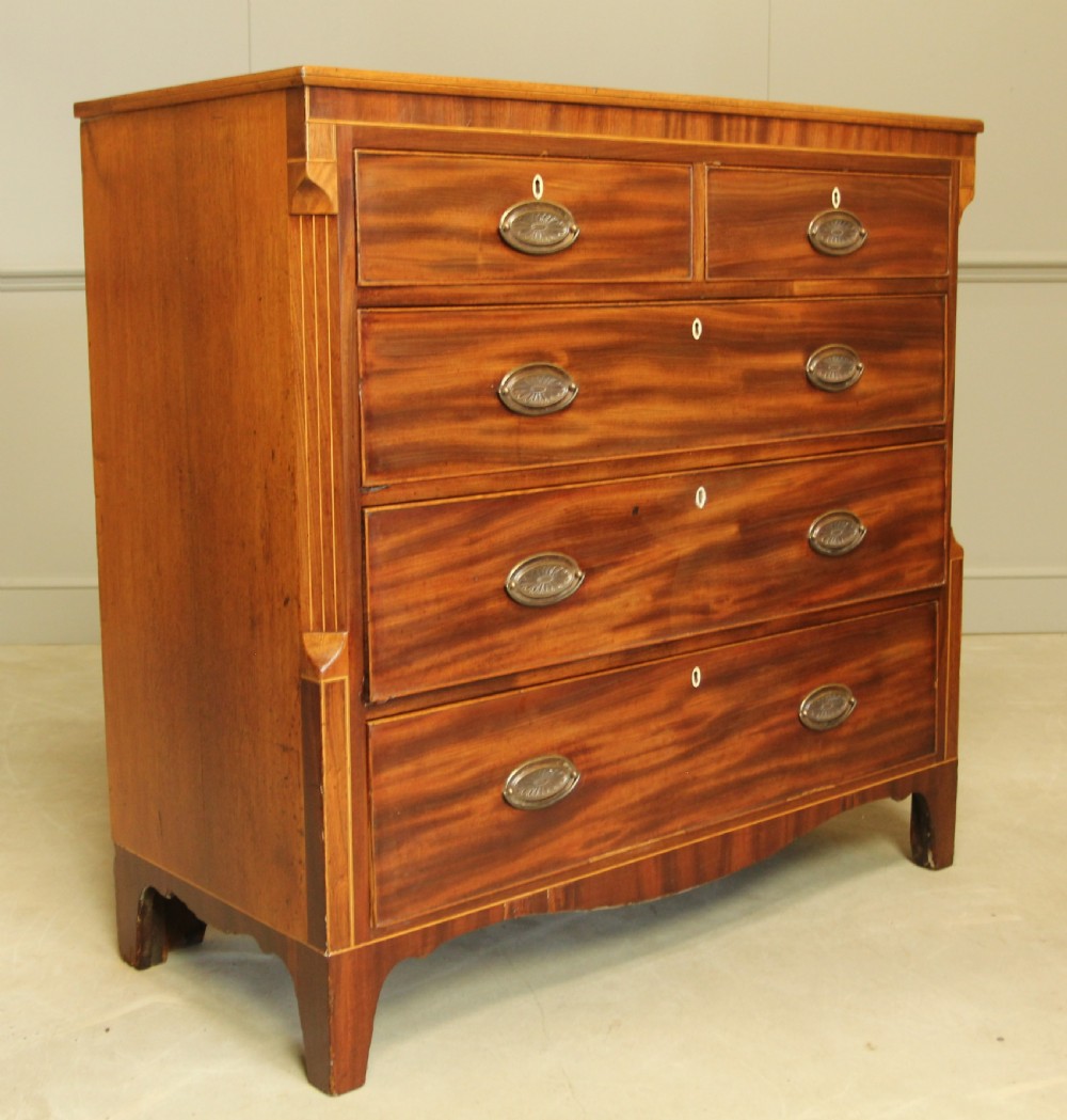 A Victorian flame mahogany chest of drawers featuring boxwood inlay, two short drawers over three long drawers, oval brass handles, and splayed bracket feet. View II