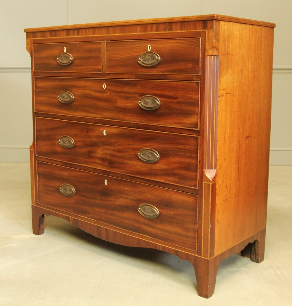A Victorian flame mahogany chest of drawers featuring boxwood inlay, two short drawers over three long drawers, oval brass handles, and splayed bracket feet. View III