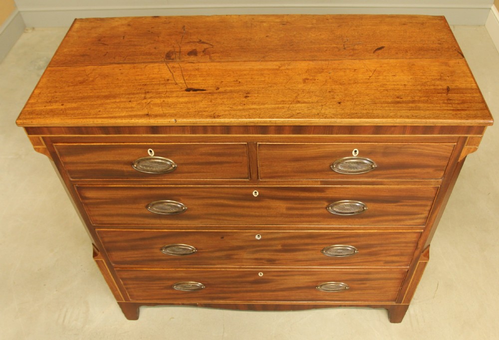 A Victorian flame mahogany chest of drawers featuring boxwood inlay, two short drawers over three long drawers, oval brass handles, and splayed bracket feet. View VII