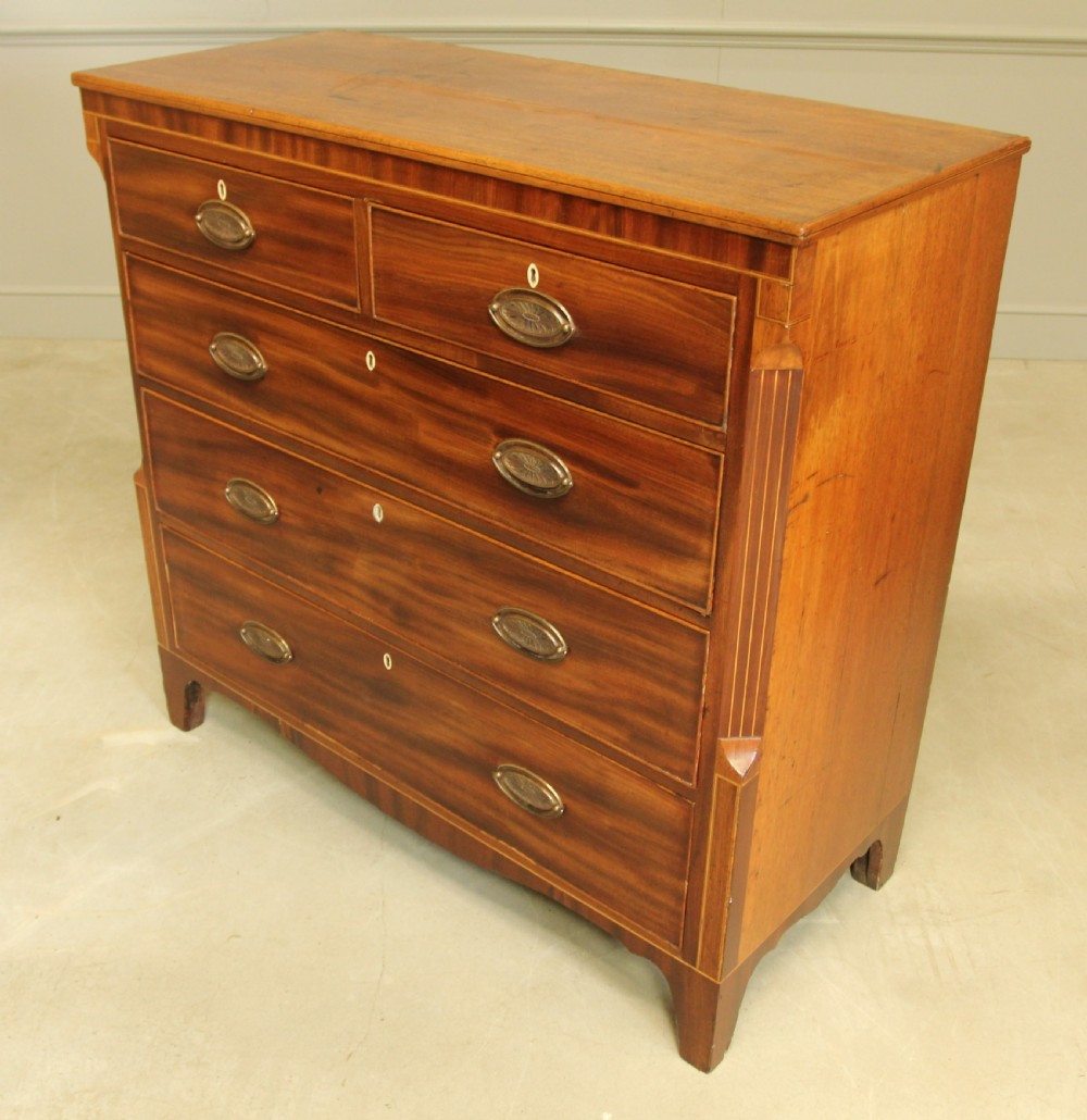 A Victorian flame mahogany chest of drawers featuring boxwood inlay, two short drawers over three long drawers, oval brass handles, and splayed bracket feet. View IX