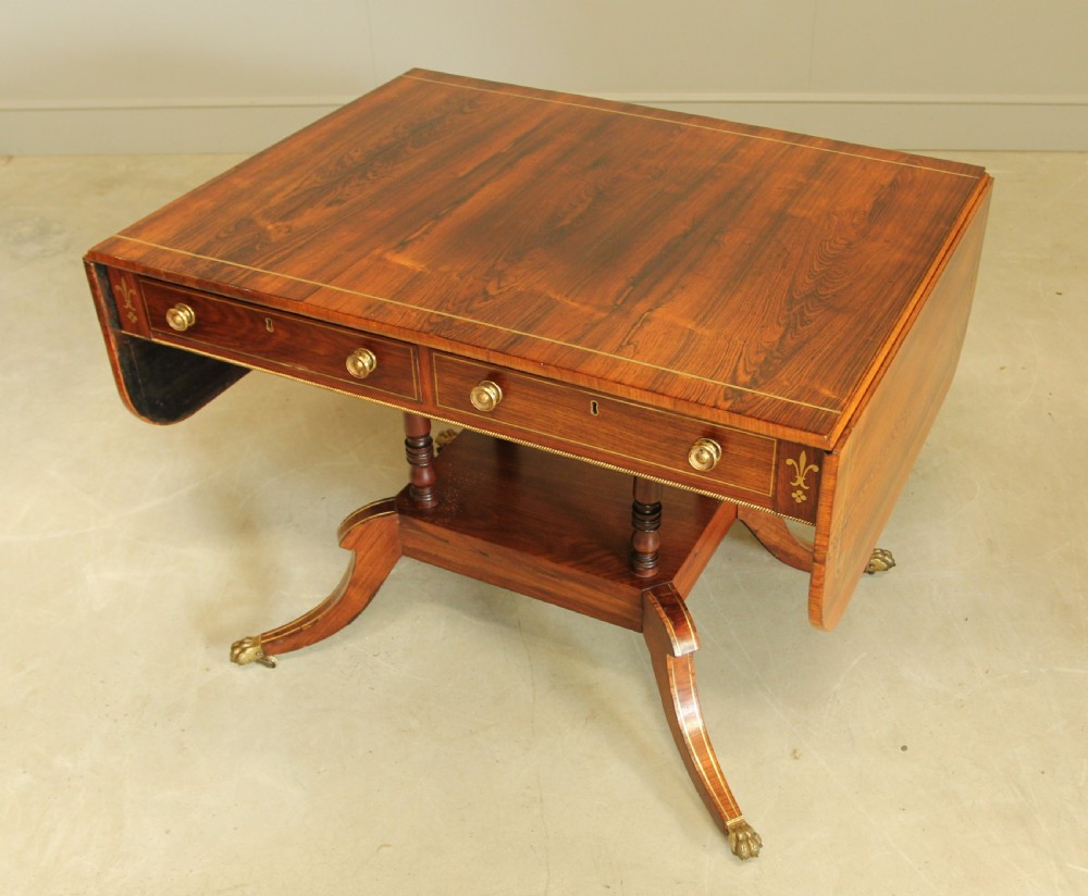 A Regency rosewood sofa table featuring brass stringing inlay, two frieze drawers, twin turned pedestal columns, and splayed legs with brass paw feet. View III