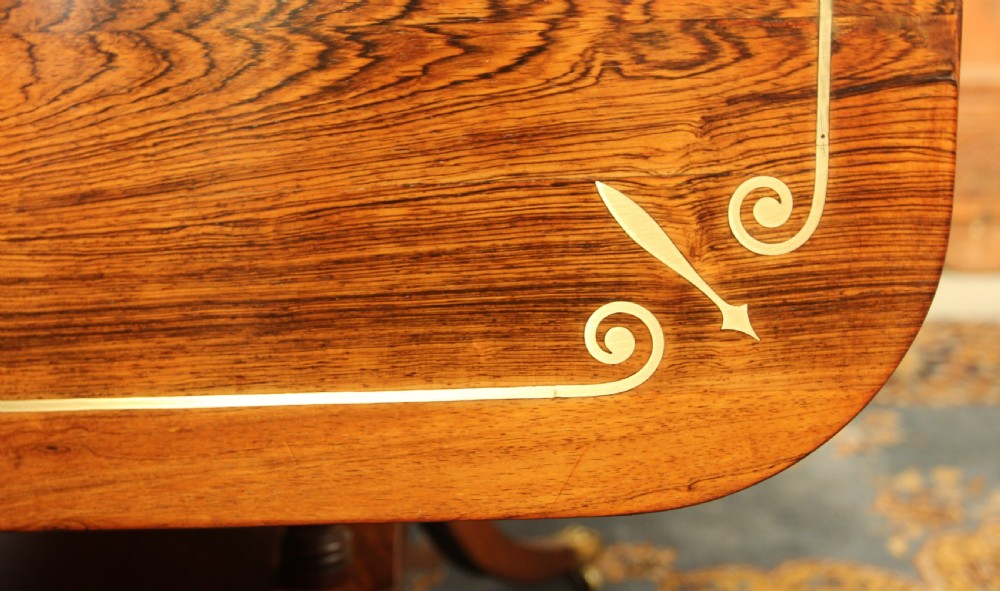 A Regency rosewood sofa table featuring brass stringing inlay, two frieze drawers, twin turned pedestal columns, and splayed legs with brass paw feet. View XII